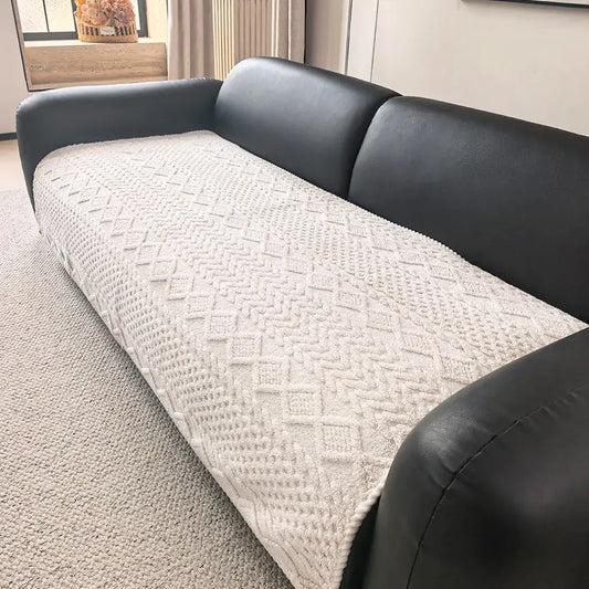 Off white Akina jacquard sofa cover gripping a black leather sofa seat