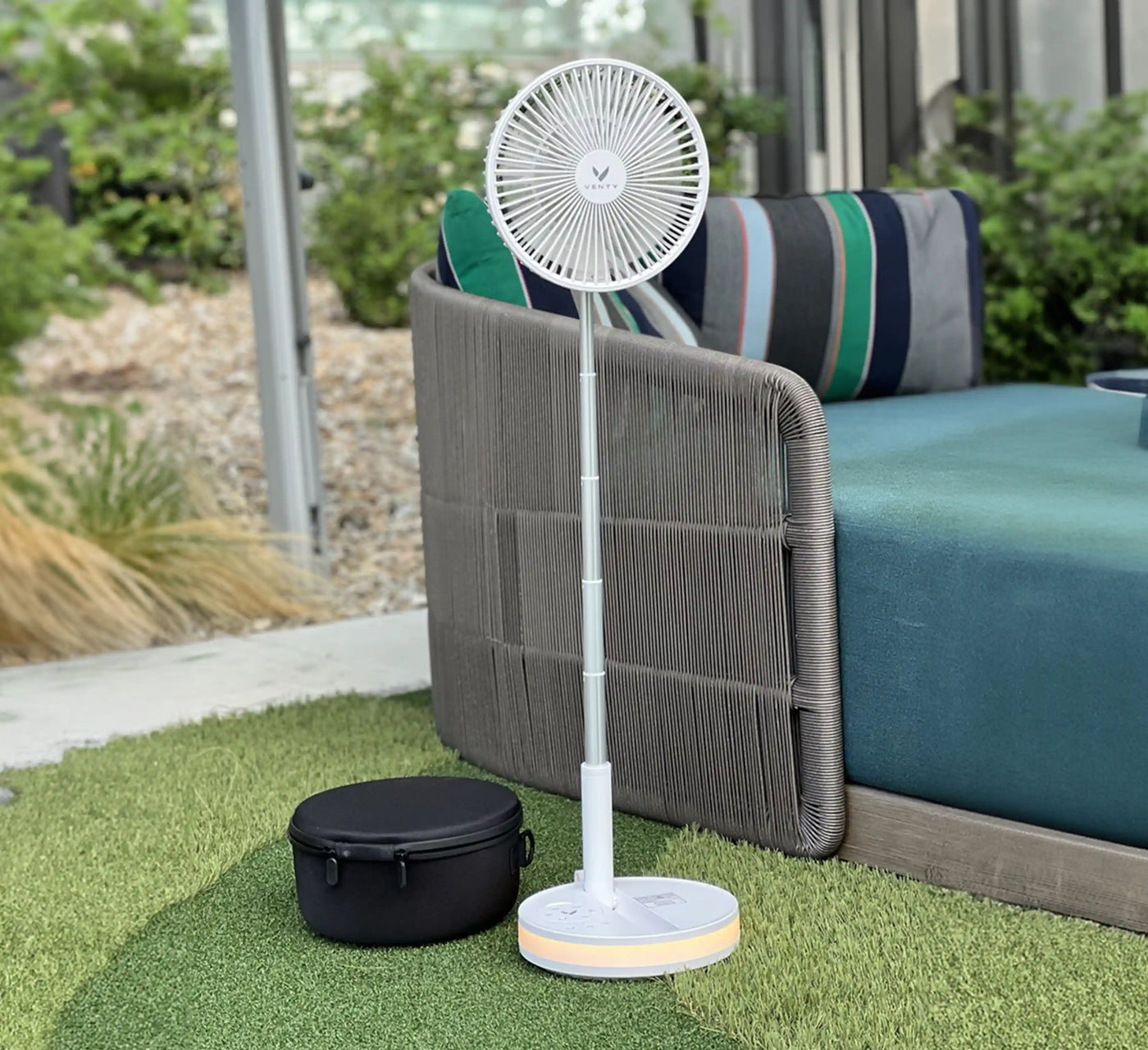 Folded Akina Portable Fan being tucked into a woven travel basket, ready to slip into any bag