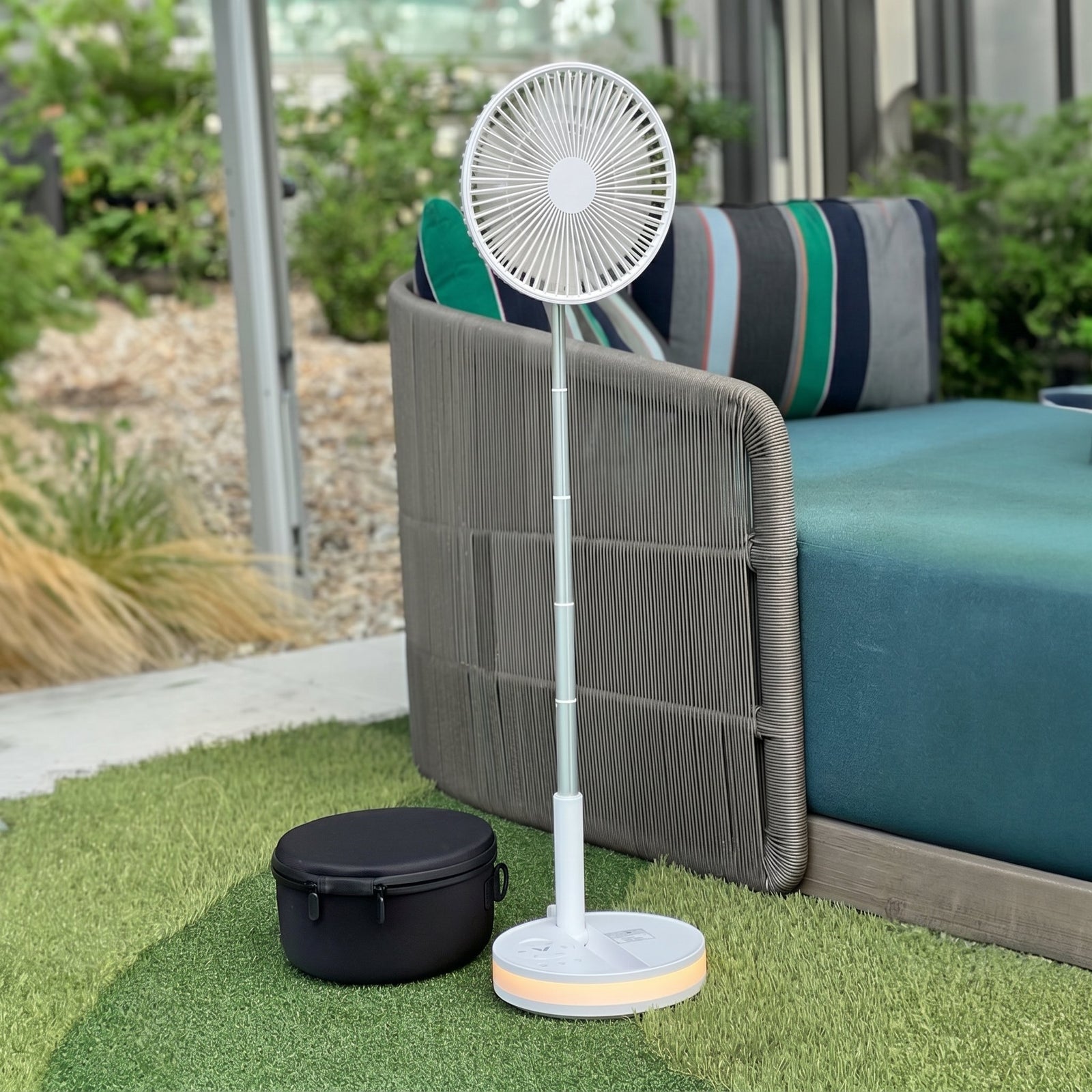 Folded Akina Portable Fan being tucked into a woven travel basket, ready to slip into any bag